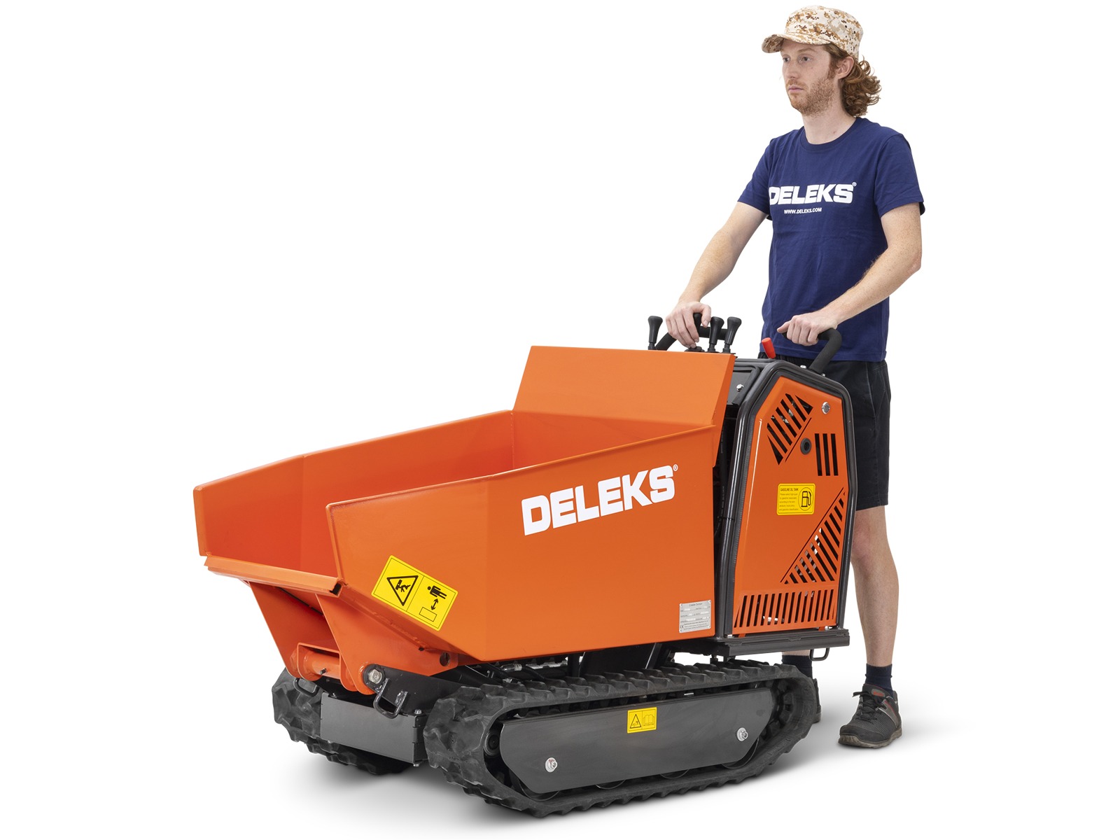 Sinises DELEKSi T-särgis olev isik juhib oranži värvi Deleks roomikminidumper M5000 BS kummirajadega, seljas lühikesed püksid ja mustriline müts, valge taustaga.