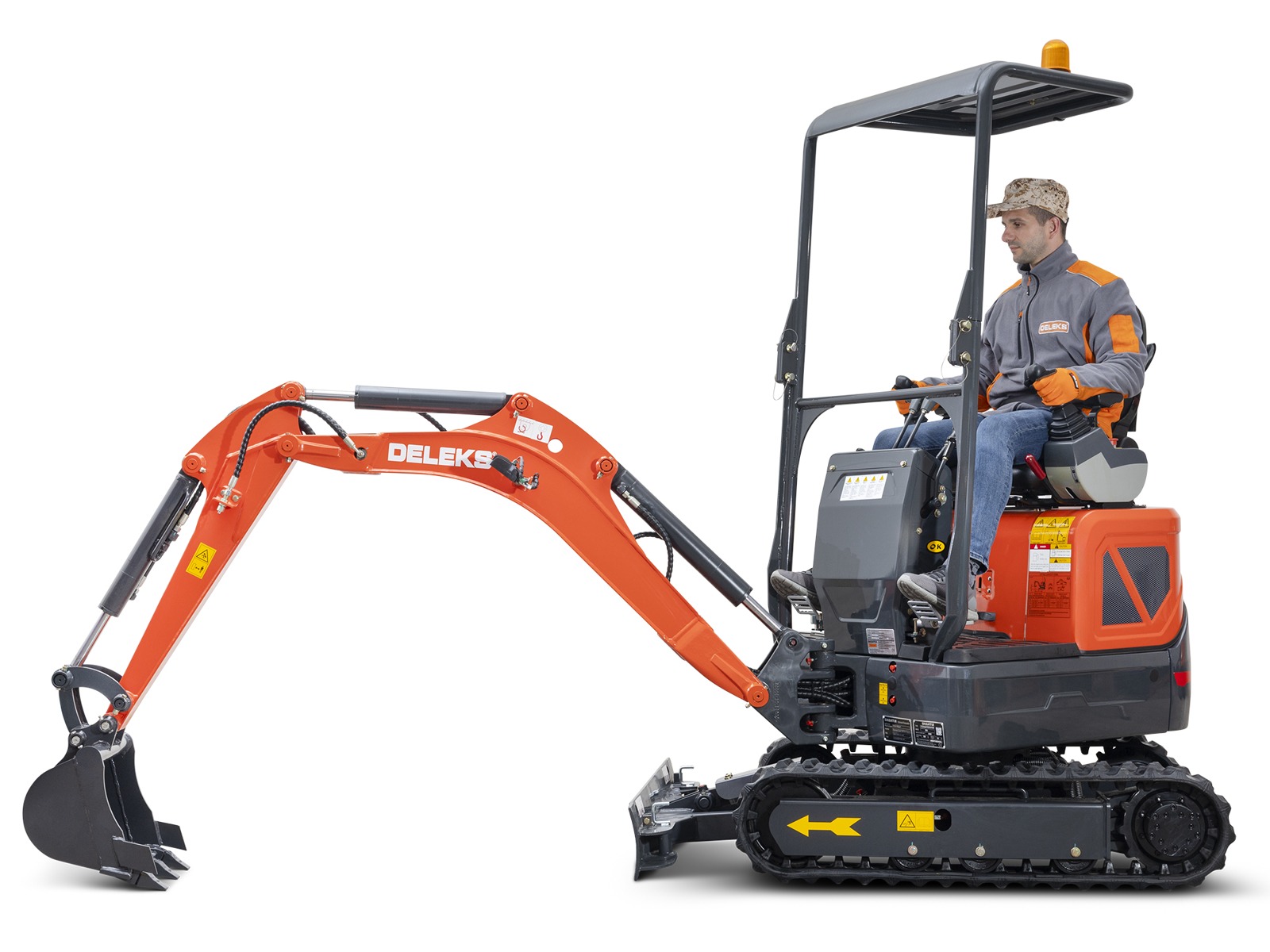 Tööriietes ja mütsiga mees juhib Deleks S120 KUBOTA miniekskavaatorit - oranži värvi kompaktset ekskavaatorit, millel on mustad rööpad, väike kaevekopp ja DELKE logo käe peal.