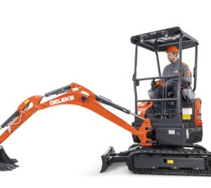 Kiivri ja töövormi kandev mees töötab Deleks S180 KUBOTA miniekskavaatoriga koos kaevanduskühvliga, küljelt vaadatuna valgel taustal.